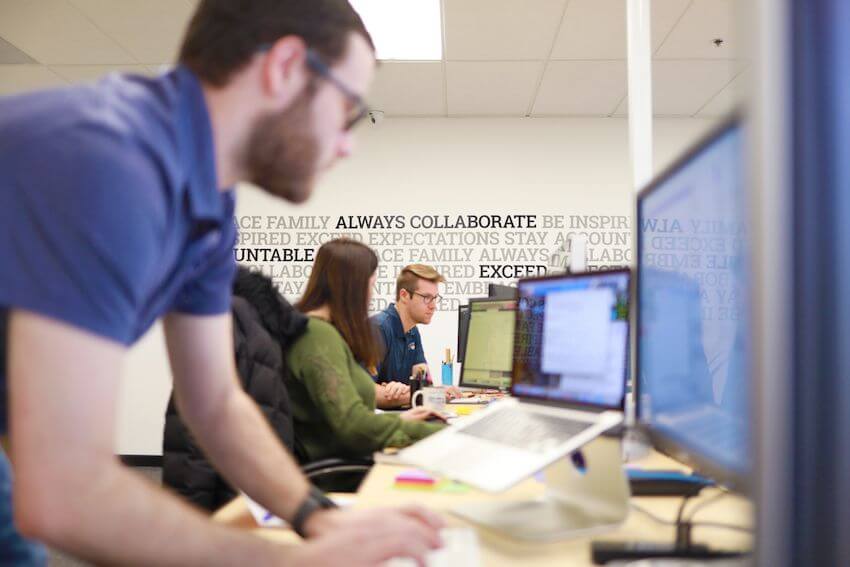 employees at desks open workspace core values on wall